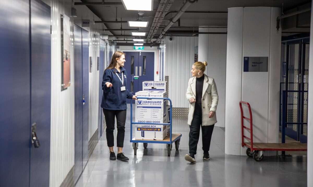 A photo showing a Vanguard employee helping a customer take some boxes into a storage unit at one of Vanguard's self storage branches.