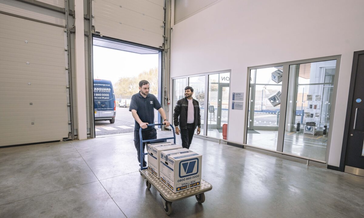 A photo showing a Vanguard employee pushing a trolley with Vanguard cardboard boxes on it for a customer.