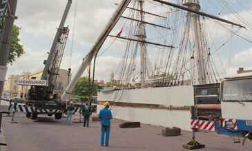An old photo showing a large boat next to a Vanguard crane.