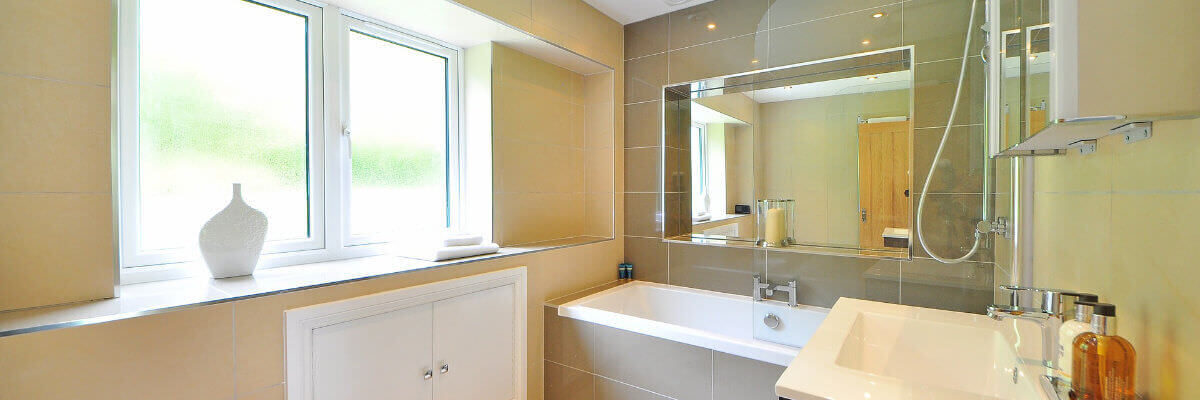 A photo showing a large bathroom with a sink and bathtub against a big window.