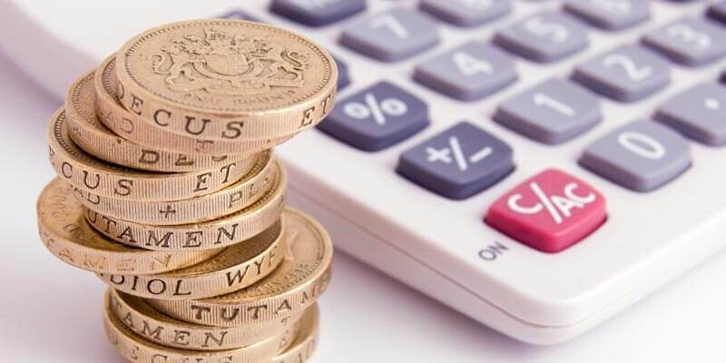 A photo showing a stack of old one pound coins next to a calculator.
