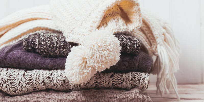 A photo showing a stack of folded knitwear and jumpers.