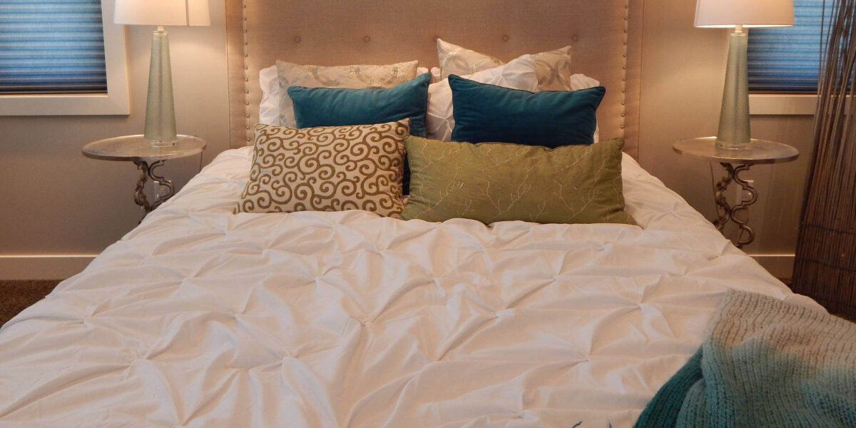 A photo showing a bed with two bedside tables and lamps on either side.