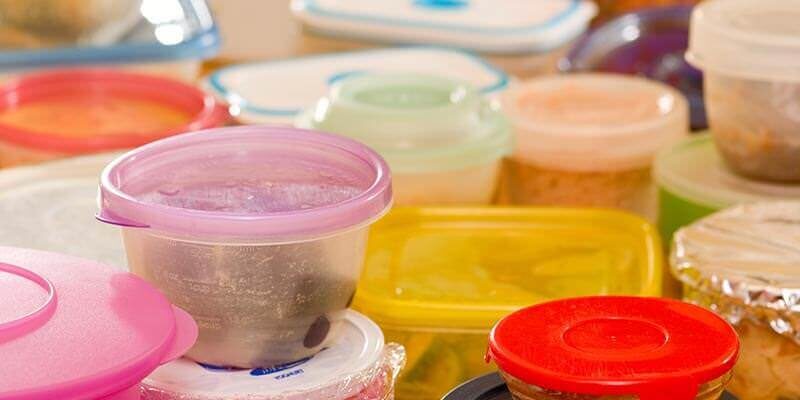 A photo showing a large number of full tupperware boxes on a table.
