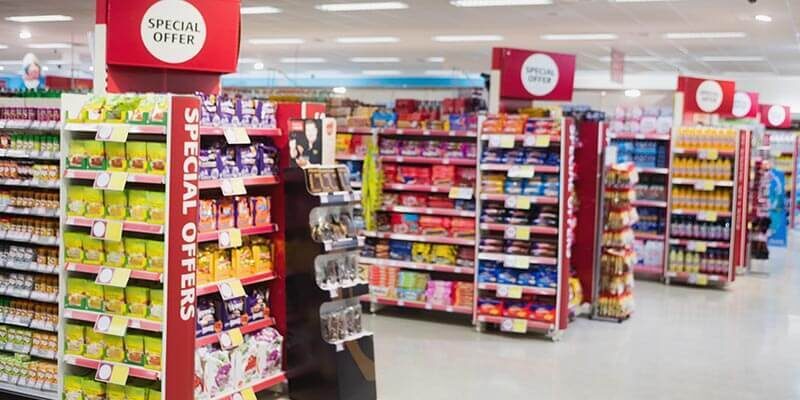 A photo showing the inside of a supermarket with special offer signs on top of each aisle.