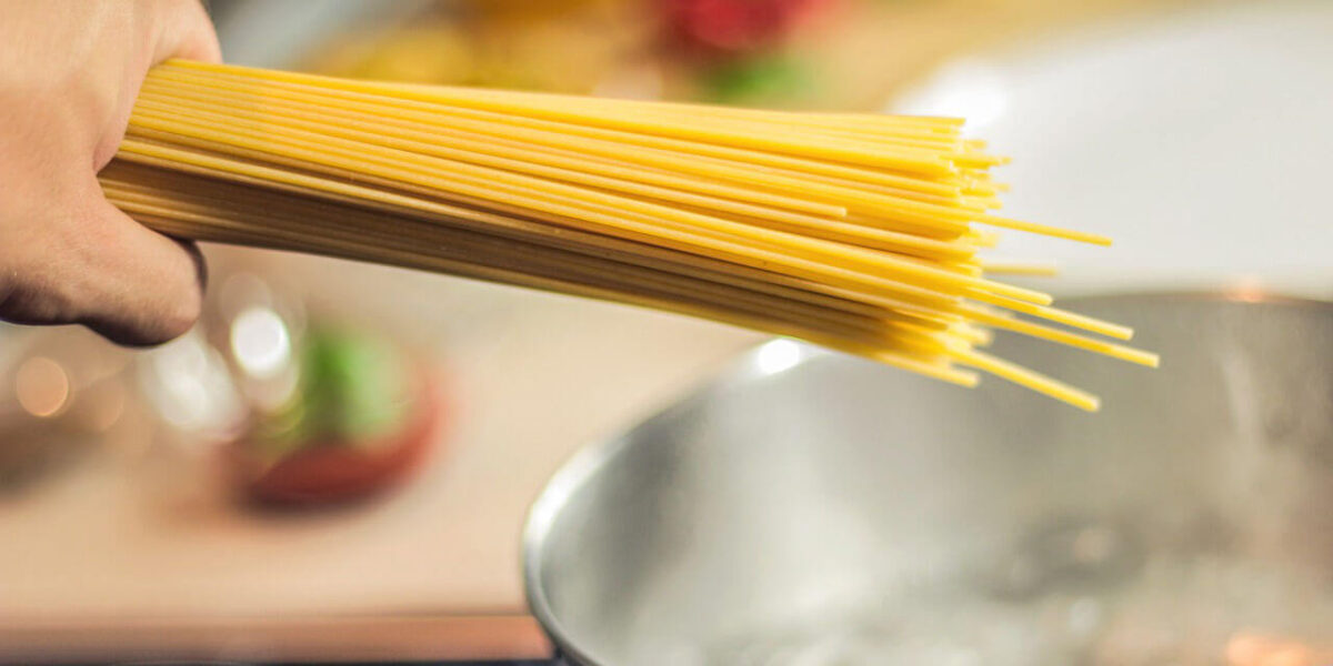 A close-up photo of spaghetti being thrown inside a pot of boiling water.