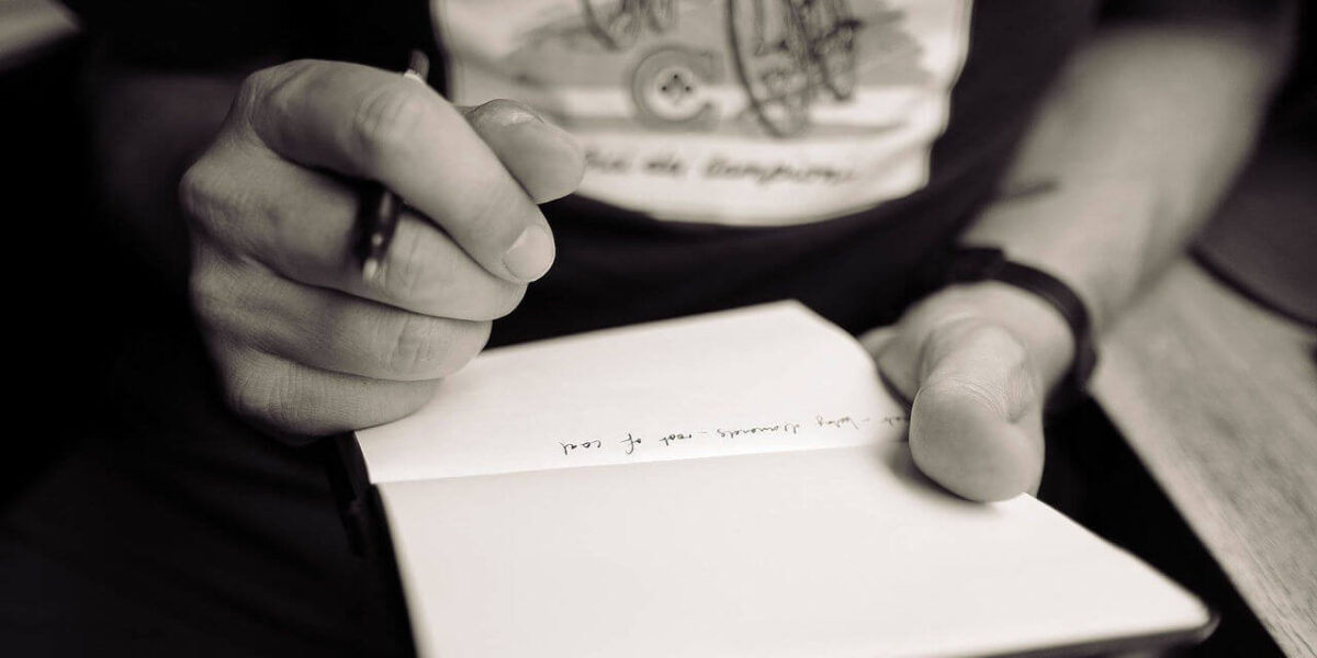 A photo showing a person taking notes using a pen and paper.