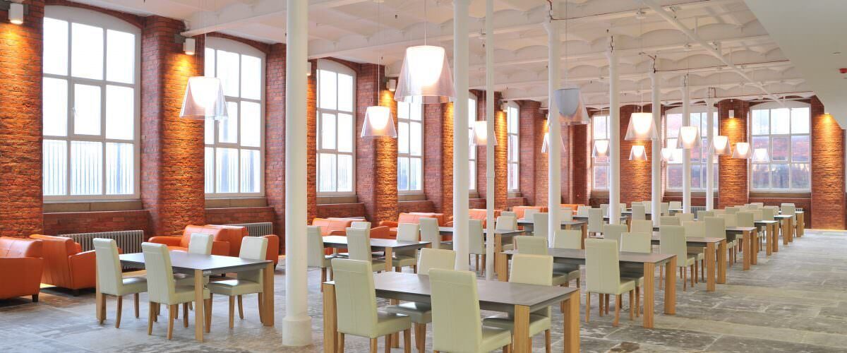 A photo showing many tables and chairs inside a dining room.