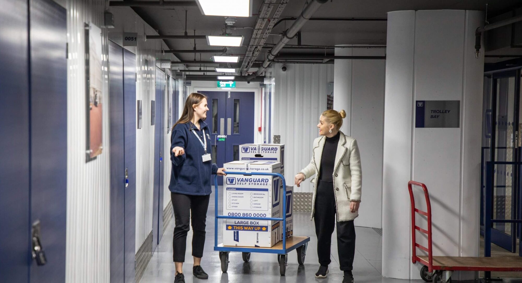 A photo showing a Vanguard employee pushing a trolley with Vanguard cardboard boxes to a customer's self-storage unit.