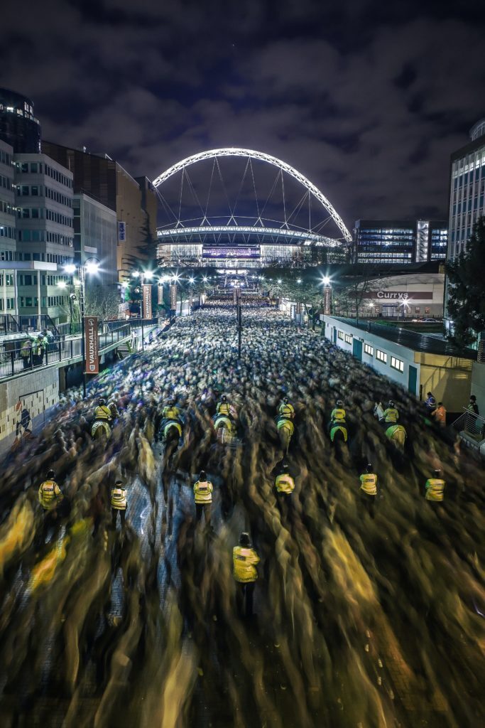 A photo showing large masses of people leaving the Wembley Stadium at night.