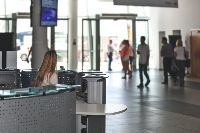 A photo showing a woman working behind the reception of a building.