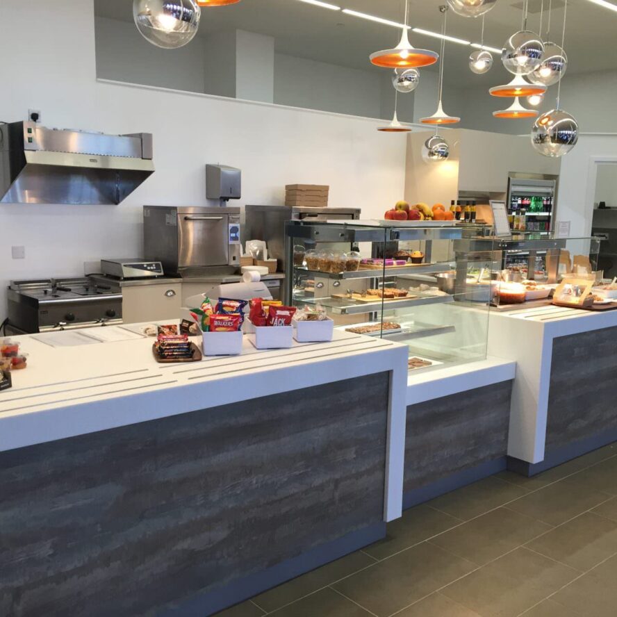 A photo of the inside of a restaurant with a counter full of food.