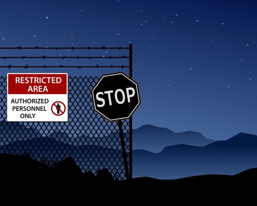 A photo showing a stop sign by a fence indicating a restricted area.