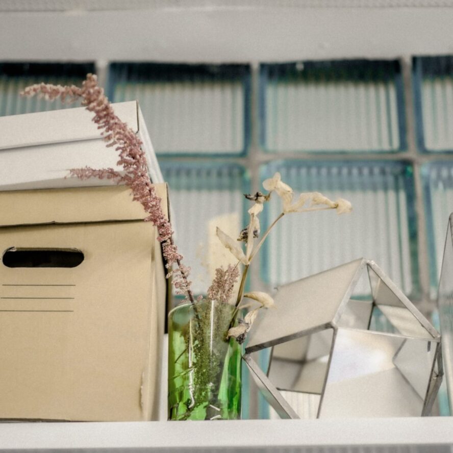 A photo showing a file storage box, some flowers in a vase and a smaller storage box on top.