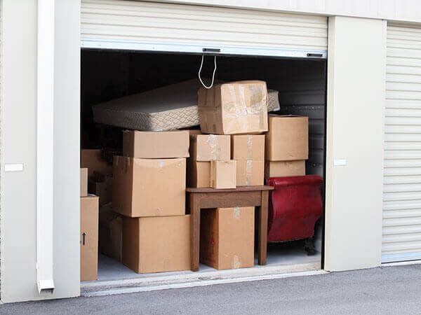 A photo showing a self-storage unit fully packed with boxes and furniture.