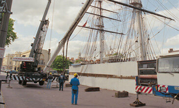 An old photo showing a large boat next to a Vanguard crane.