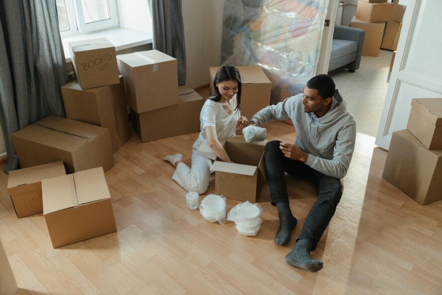 A photo showing two people packing cardboard boxes for a move.